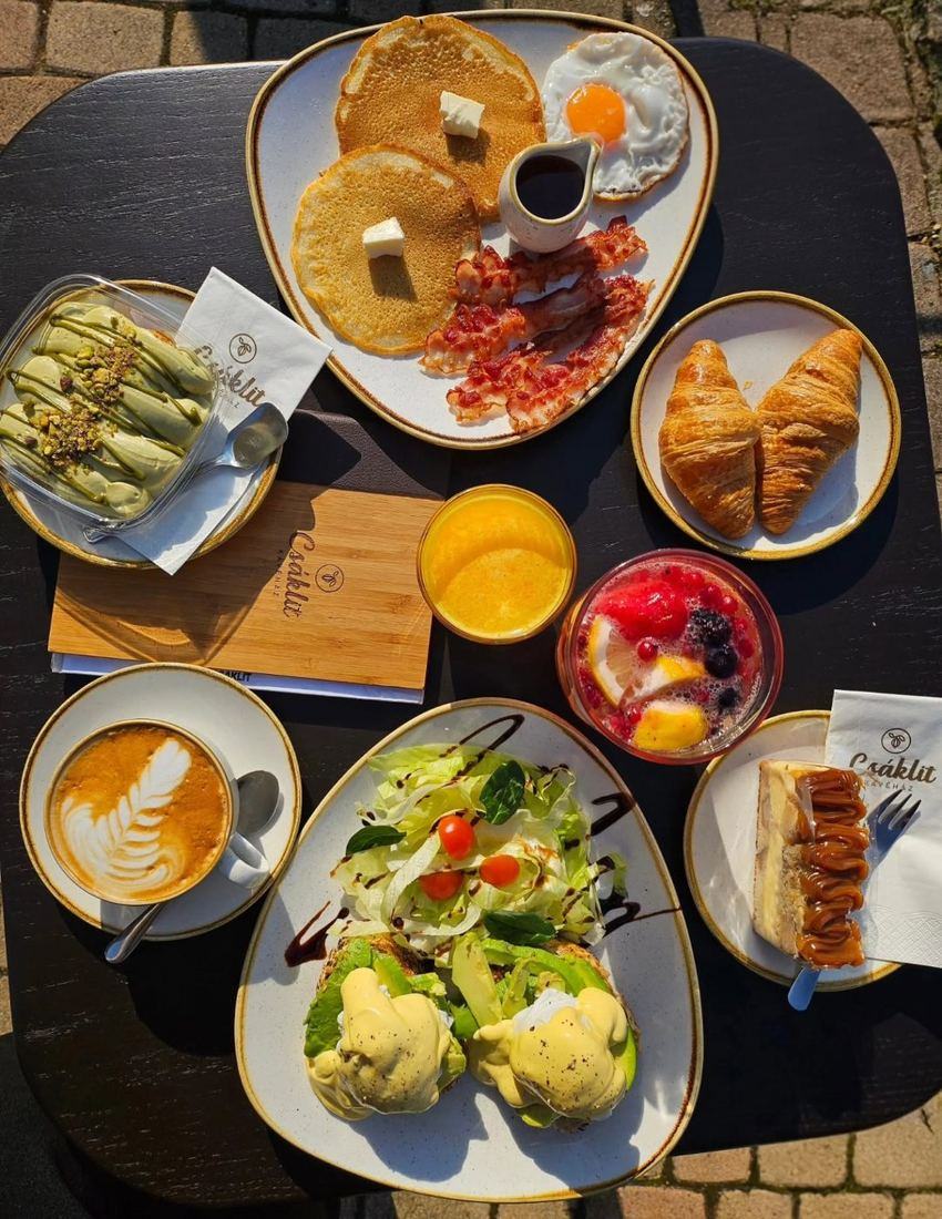 Megterített reggeliző asztal palacsintával, eggs benedicttel, croissant-nal, friss narancslével és cappuccinóval